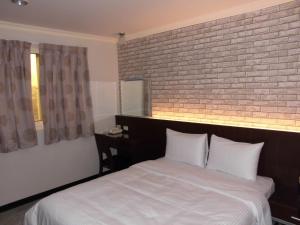 頭份市的住宿－欣悅商務旅店，卧室配有白色的砖墙床