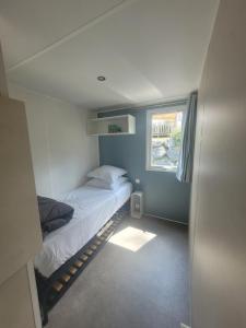 a small bedroom with a bed and a window at Mobil-home MJ in Seignosse +11 photos