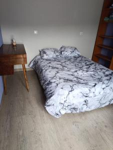 a bed with a black and white comforter and a table at chez MAG et YANN in La Séauve-sur-Semène