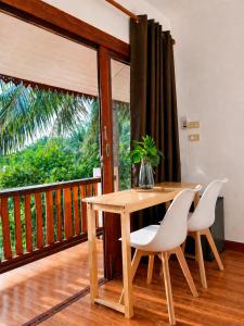 a wooden table with white chairs and a wooden balcony at Nami by Secret Place in Mae Haad