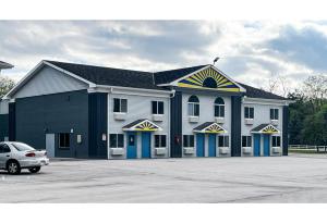a large building with a car parked in a parking lot at Studio 6 Suites - Tiffin, OH in Tiffin