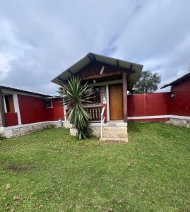 a red house with a palm tree in front of it at Cabañas ALAMEDA in Omitlán de Juárez