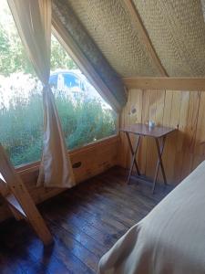 a room with a bed and a table and a window at Cabañas Alma Serrana in San Jose del Pacifico