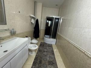 a white bathroom with a toilet and a sink at Edelweiss in Almaty +8 photos