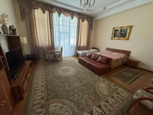 a bedroom with a bed and a couch and a television at Edelweiss in Almaty