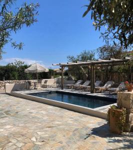 a swimming pool with chairs and an umbrella at Villa Vivari Suites in Vivari
