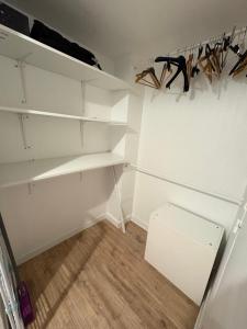a closet with white shelves and a white refrigerator at Large Studio Near Train station and Disney in Lognes
