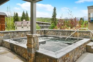 a hot tub in a stone retaining wall with a patio at Downtown WP Corner Loft 24 I Hot Tub I Great Views I Bunk Beds I Activity Program in Winter Park