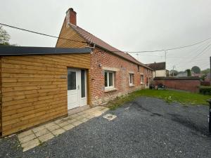 a brick house with a white door and a garage at La Clef des Champs in Mecquignies