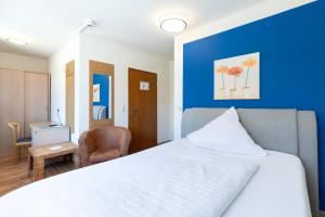 a bedroom with a white bed and a blue wall at Hotel an der Hörn in Kiel