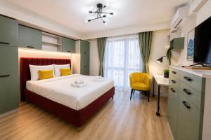 a bedroom with a bed with a yellow chair and a desk at Victoriei Studio Old City in Bucharest