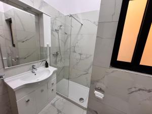 a white bathroom with a sink and a shower at Brand new Oceanview Penthouse by MaBeLi in St. Paul's Bay