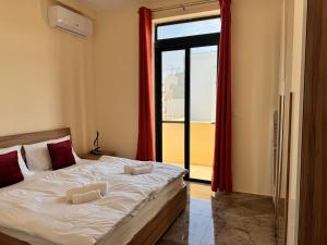 a bedroom with a bed with red curtains and a window at Brand new Oceanview Penthouse by MaBeLi in St. Paul's Bay