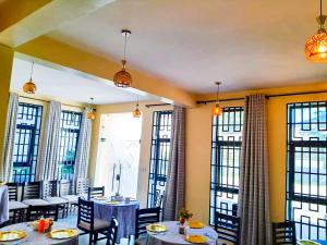 a restaurant with tables and chairs and large windows at RIVANA HOTEL Goba in Dar es Salaam
