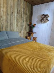a bedroom with a yellow bed and a wooden wall at Cabañas Alma Serrana in San Jose del Pacifico +17 photos