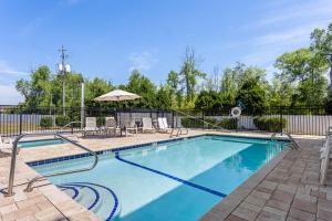 a swimming pool with chairs and an umbrella at Clarion Pointe Jesup in Jesup