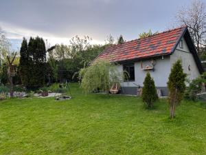 a small white house with a red roof in a yard at Chatka nad stawem in Radłów