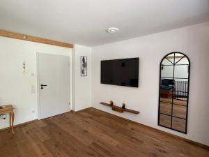 a living room with white walls and a flat screen tv at Ferienwohnung Andreas in Holzkirchen