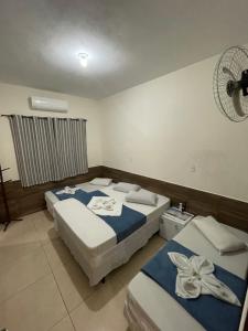 a bedroom with two beds and a fan at Pousada Imperatriz in Aparecida