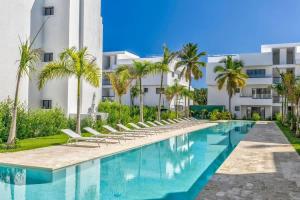 a swimming pool with lounge chairs in front of a building at Private Beach Community - White Sands Golf Resort - Modern 2BR Private Pool and Patio in Punta Cana