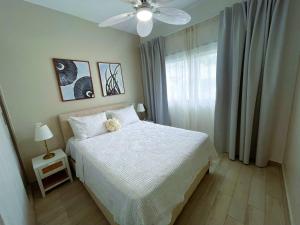 a bedroom with a white bed and a ceiling fan at Private Beach Community - White Sands Golf Resort - Modern 2BR Private Pool and Patio in Punta Cana +35 photos