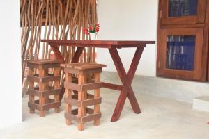 a wooden table and two stools next to a wall at Miu Villa in Ahangama