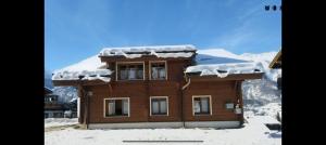 a wooden house with snow on the roof at Chalet Adler in Grächen