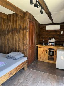 a wooden room with a bed and a kitchen at Shulgivka in Shulʼgovka