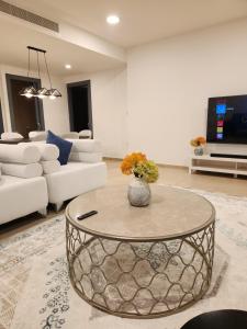 a living room with a vase with flowers on a table at Premium 2 Bedroom Apartment Near Airport in Muscat