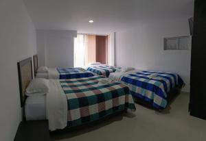 a bedroom with three beds in a room at Hotel the Blue House in Ipiales
