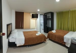 a hotel room with two beds and a television at Hotel the Blue House in Ipiales