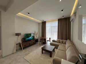 a living room with a couch and a tv at Sea Breeze Polo Residence in Baku