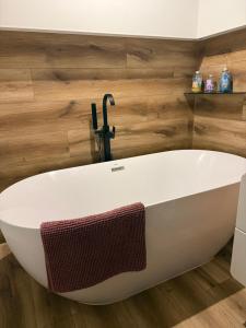a white bath tub in a bathroom with wooden walls at Katerina - Mona Luxury Apartments in Lębork +19 photos
