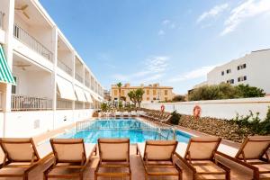 a pool in the courtyard of a hotel with chairs at Hotel S'Algaret in Fornells