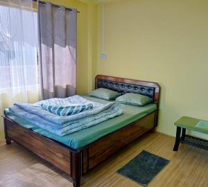 a bed with a wooden frame in a room with a window at Fun Viewpoint Homestay Darjeeling in Darjeeling