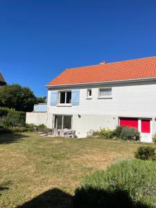 a white house with a red roof and a yard at Le Clos - Proximité plage in Ambleteuse