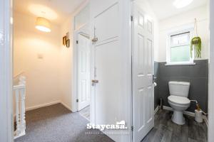 a bathroom with a toilet and a window at Spacious Cosy Cove with Large Driveway and Garden in Wythenshawe +33 photos