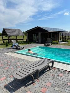 a person laying in a swimming pool with a bench at Shulgivka in Shulʼgovka