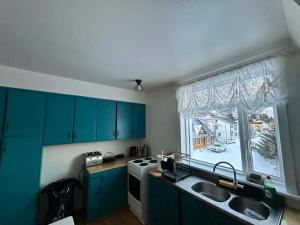 a kitchen with blue cabinets and a sink and a window at Chic Townhouse - Views Telescope Balcony BBQ in Siglufjörður