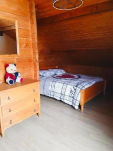 a bed in a wooden room with a teddy bear at O'Doubs Chalet in La Chaux Neuve