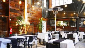 a dining room with white tables and chairs in a restaurant at Hotel Sonetto in Santiago