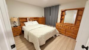 a bedroom with a bed and a dresser and a mirror at Befitting Crown Suite in Moncton +8 photos