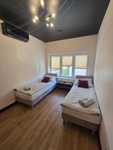 two beds in a room with wooden floors and windows at TRIO HoSteL in Hajnówka +22 photos
