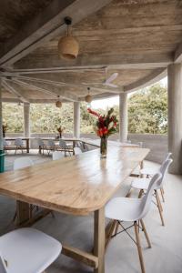 a wooden table with white chairs and a vase with flowers at Ahora Wellness Hostel in Guachaca