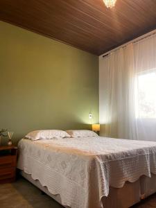 a bedroom with a white bed with a window at Recanto Miramonti Refúgio com Vista in Cristina