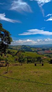 a green field with trees and a blue sky at Sitio Vale Verde da Serra in Monte Verde