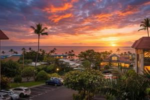 a sunset over a parking lot with cars parked at Kona Mansions#B217 Beautiful unit with Ocean view! in Kailua-Kona