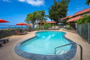 a swimming pool at a resort with benches and umbrellas at Kona Mansions#B217 Beautiful unit with Ocean view! in Kailua-Kona