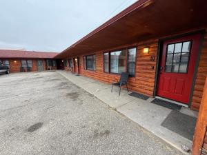 a building with a red door and a chair outside at Rustic Inn in Park Rapids