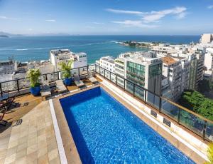 a swimming pool on top of a building with the ocean at B&B HOTEL Rio Copacabana Posto 5 in Rio de Janeiro